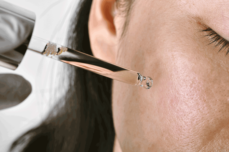retinolserum wird auf einem gesicht aufgetragen, nahaufnahme des gesichts